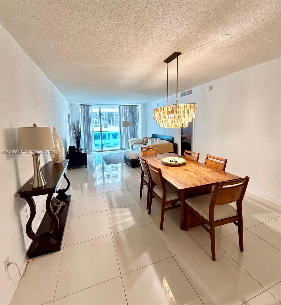 Large-format tile flooring, rectangular pendant light fixture with tiered glass elements, and floor-to-ceiling glass doors