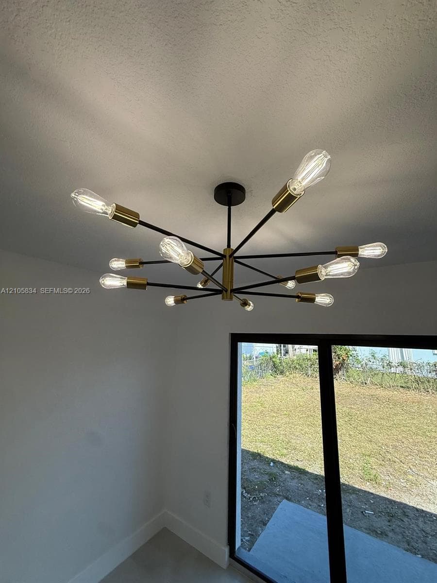 Multi-arm sputnik chandelier featuring a matte black and metallic brass finish with exposed filament bulbs, complemented by black-framed sliding glass doors