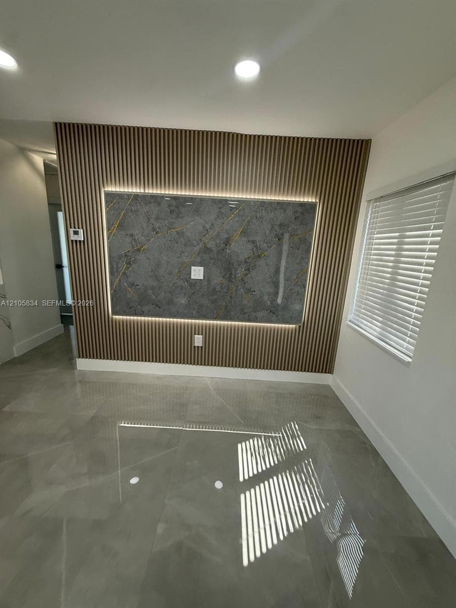Feature wall with vertical wood slats, integrated accent lighting, and a large-format stone-finish central panel, complemented by large-format tile flooring and horizontal slat blinds