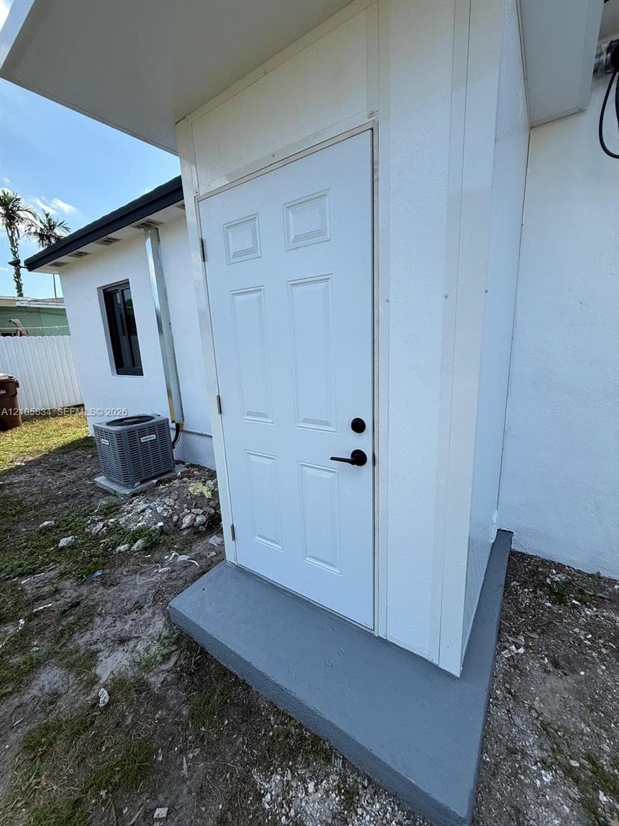 Exterior entryway featuring a six-panel white door, matte black hardware, and a painted concrete stoop