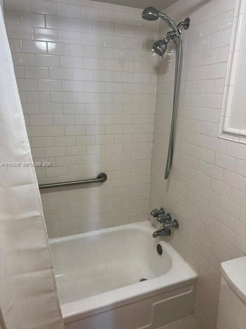 Bathtub and shower combination featuring white subway tile surround, polished chrome fixtures, and wall-mounted grab bar
