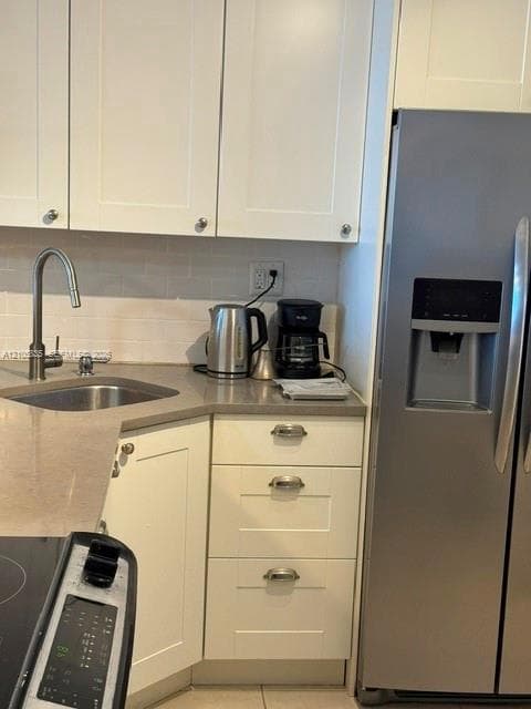 Shaker-style white cabinetry, stone-finish countertops, stainless steel side-by-side refrigerator, under-mount stainless steel sink, and arched-neck faucet