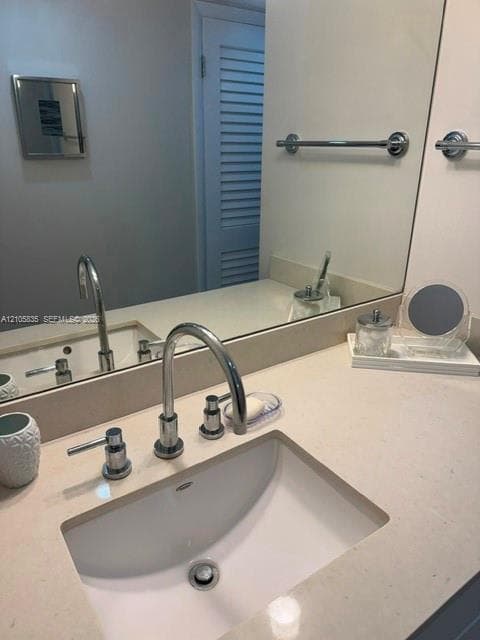 Bathroom vanity featuring a light-toned solid surface countertop, an integrated undermount sink, a chrome widespread faucet, and a large wall-mounted mirror