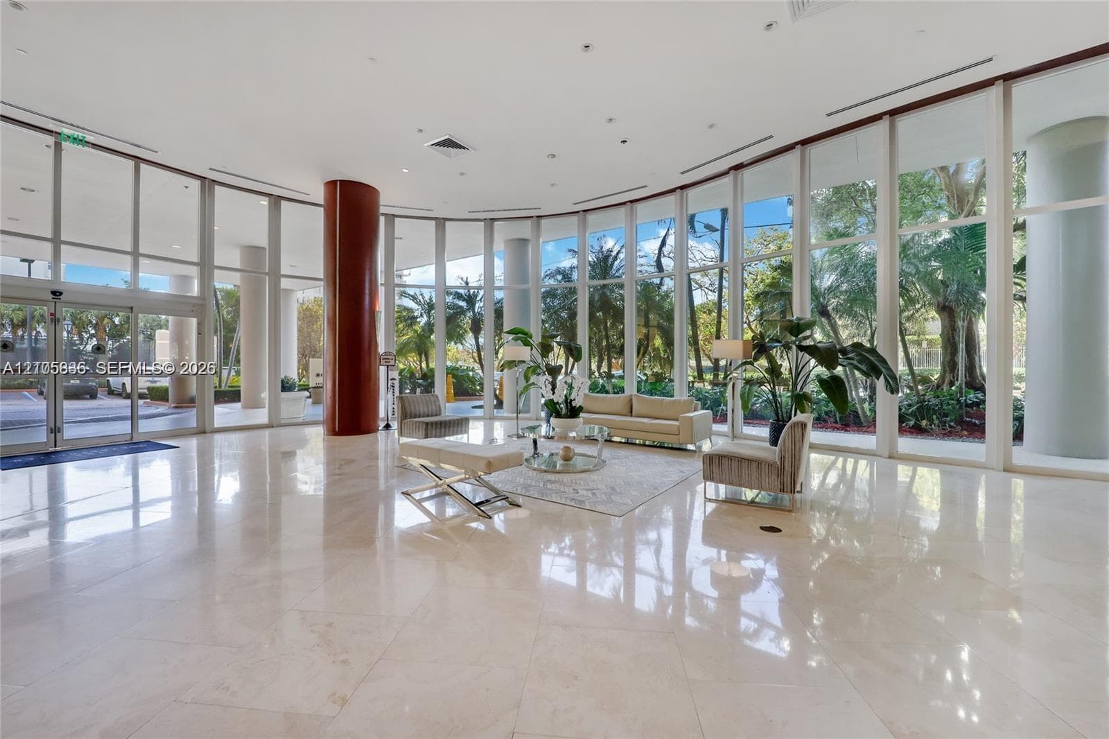 Expansive lobby featuring floor-to-ceiling glass walls, polished stone flooring, and structural columns