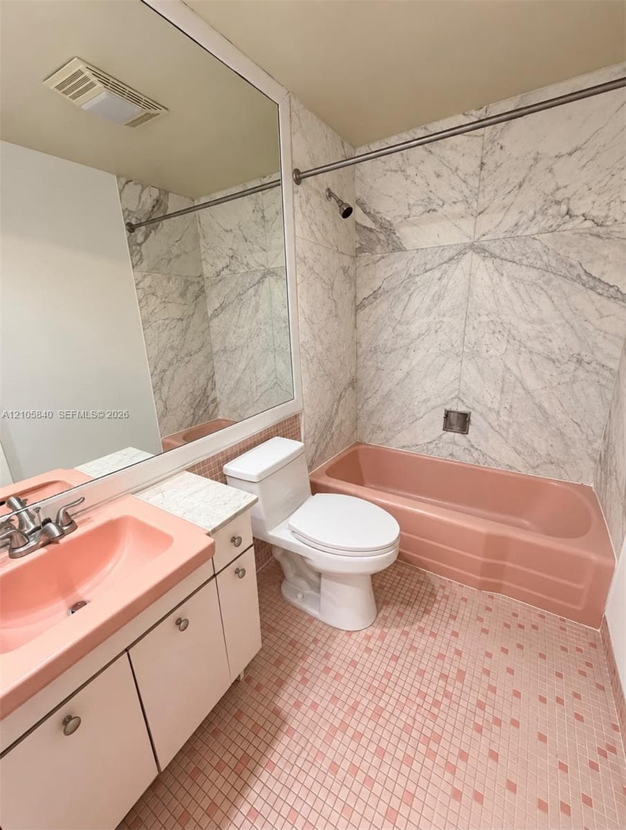 Full-wall mirror, integrated vanity with a molded basin, stone-patterned wall tile, and geometric floor tiling