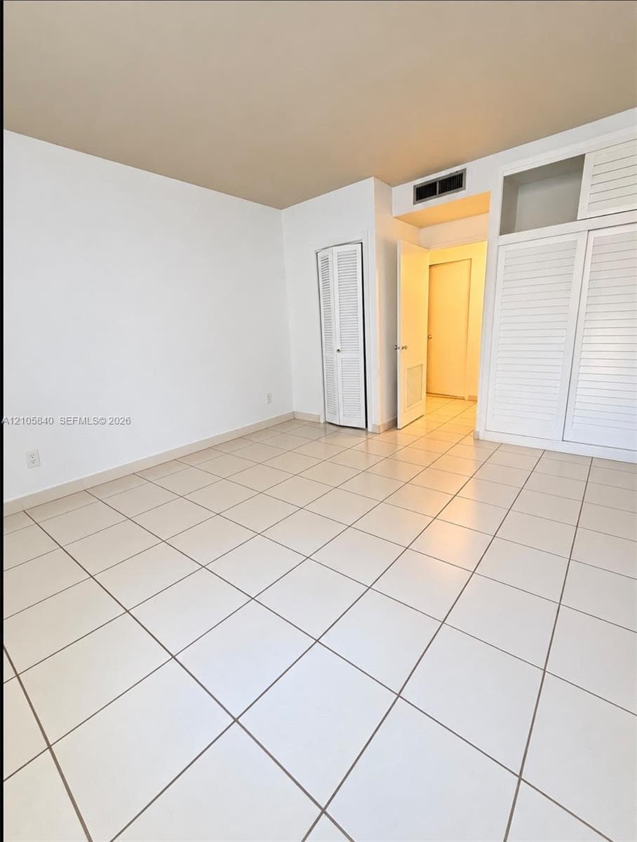 Interior room featuring large-format tile flooring, built-in floor-to-ceiling cabinetry with louvered doors, and custom overhead storage compartments