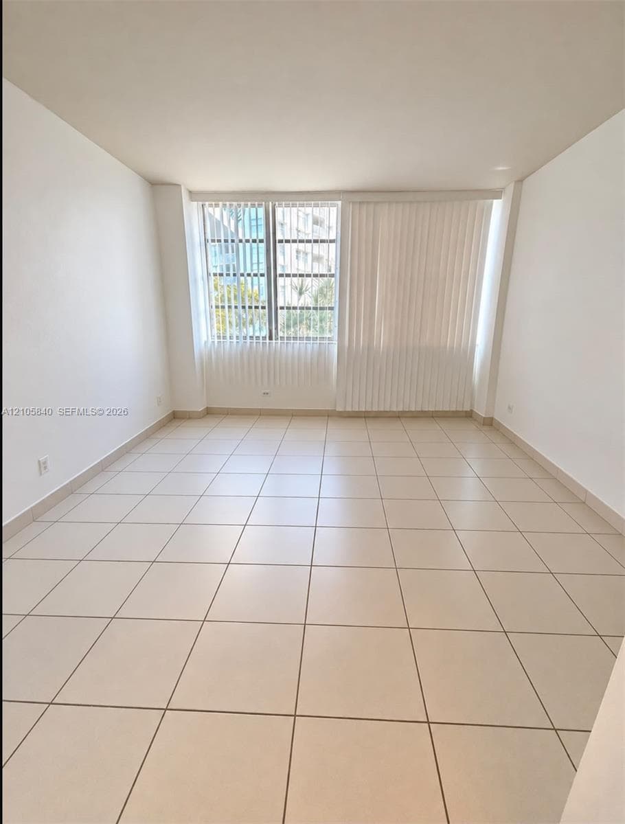 Interior space featuring ceramic tile flooring, neutral walls, and large windows with vertical blinds