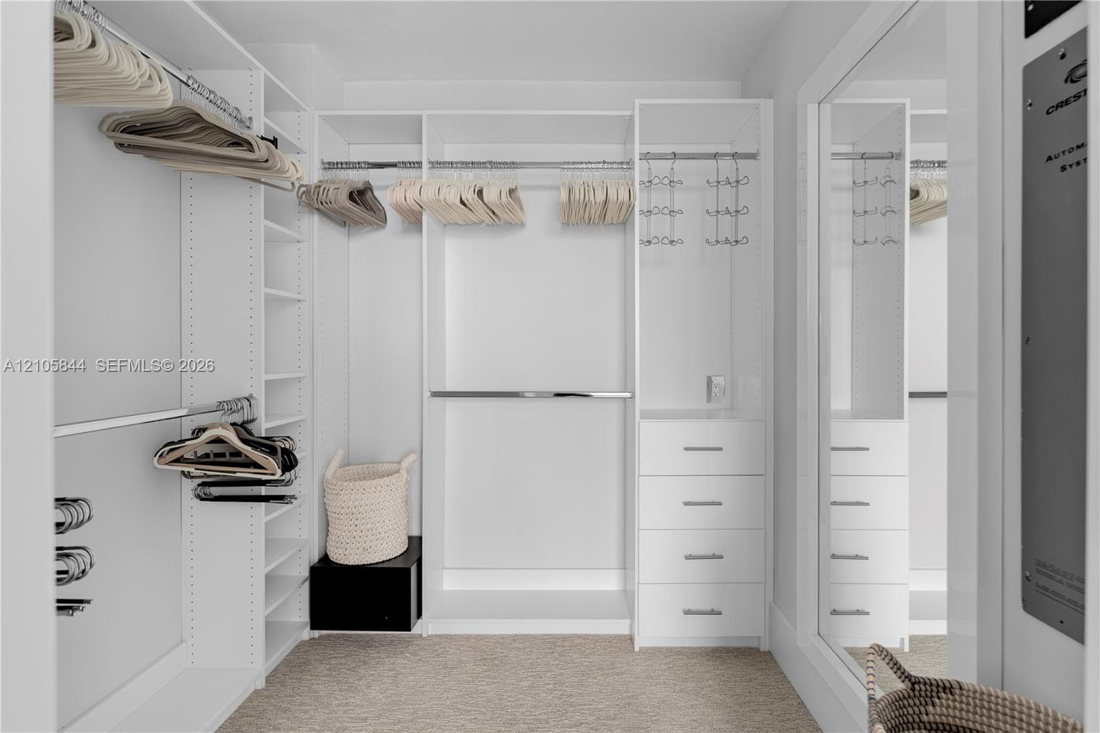 Walk-in closet featuring white custom built-in cabinetry, floor-to-ceiling shelving, multiple chrome hanging rods, and a four-drawer storage unit