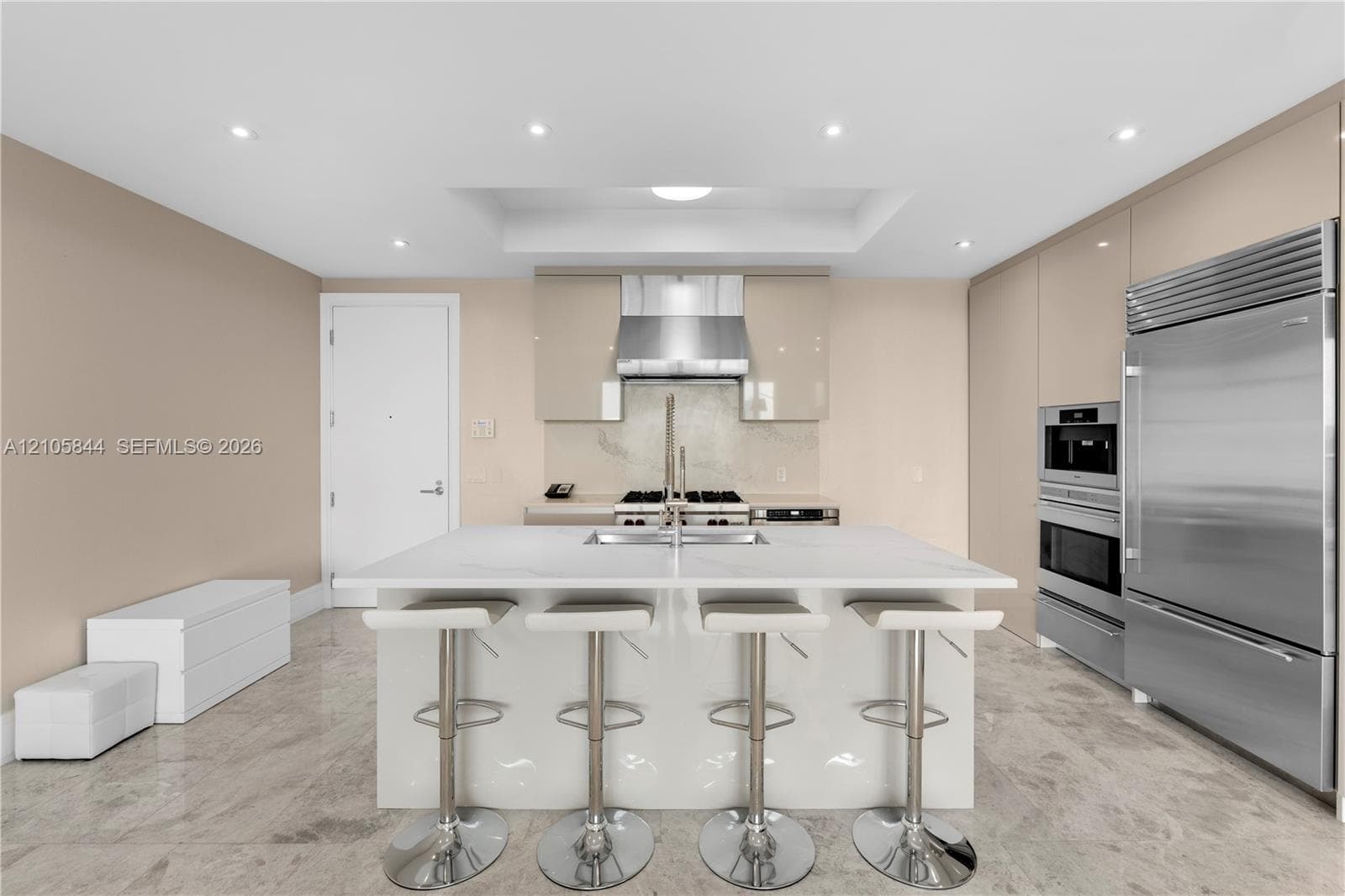 Kitchen featuring a central island with quartz countertop, high-gloss cabinetry, stainless steel professional-grade appliances, recessed lighting, and stone flooring