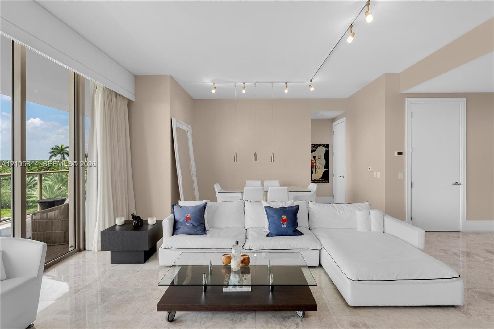 Interior living space featuring light-toned stone flooring, floor-to-ceiling glass panel doors, and overhead track lighting