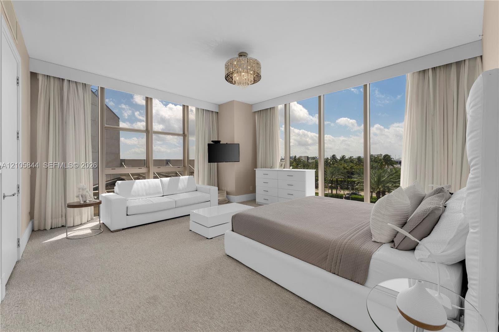 Floor-to-ceiling windows, neutral carpeting, crystal-accented flush mount lighting, and custom-fit window treatments