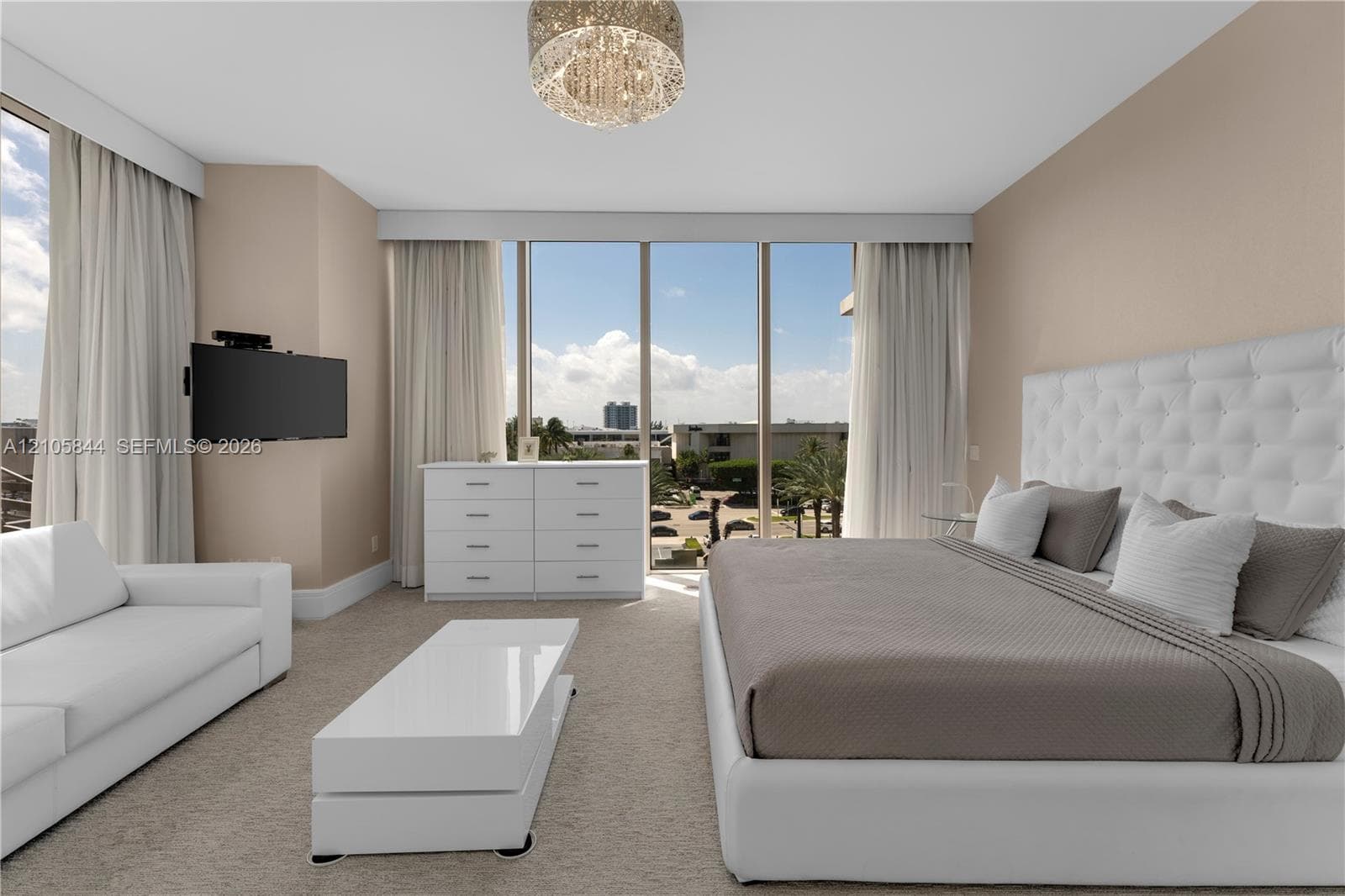 Floor-to-ceiling windows, neutral carpeting, recessed ceiling lighting, and a crystal-style chandelier
