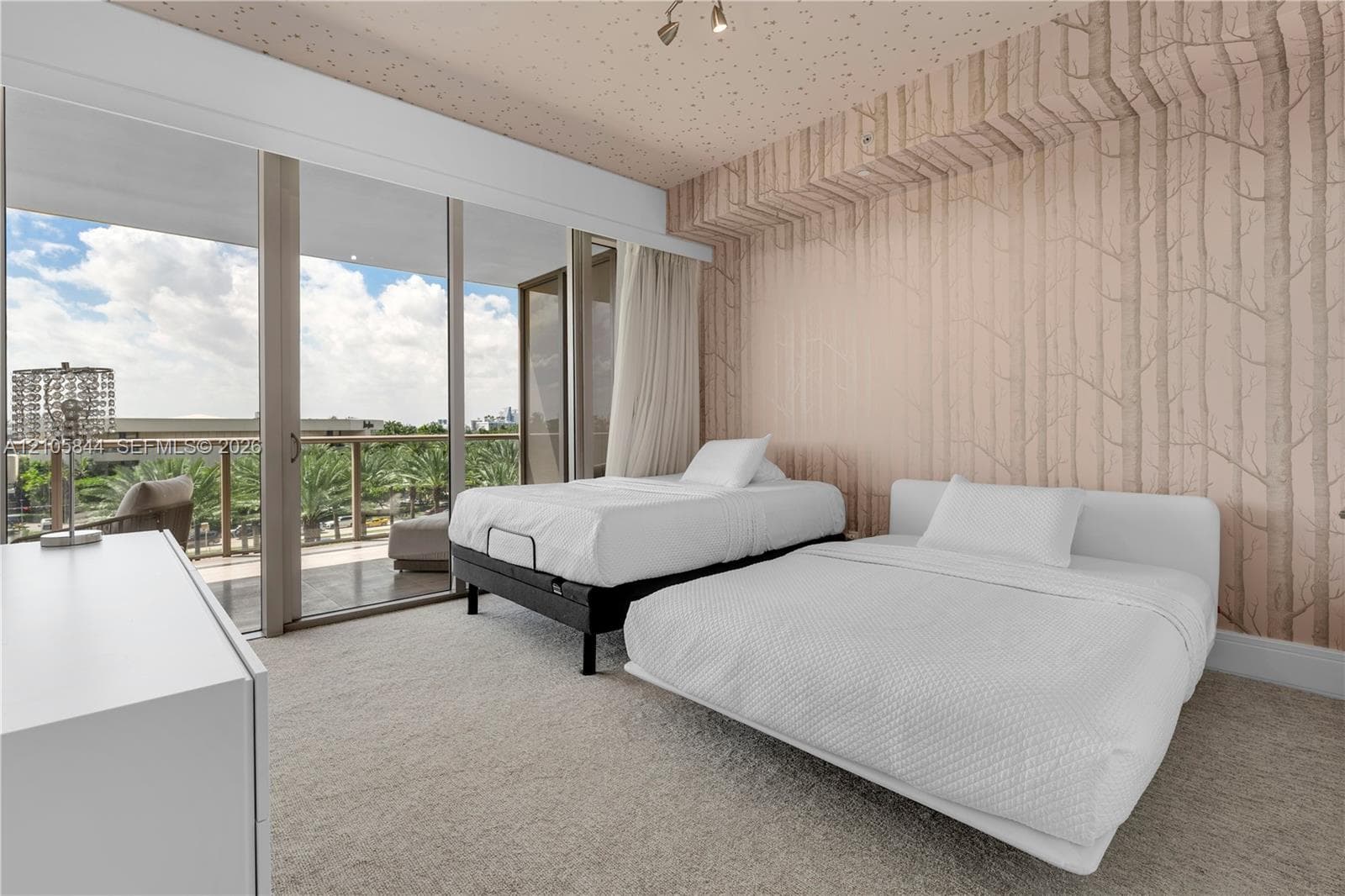 Floor-to-ceiling glass sliding doors, private balcony with metal railing, wall-to-wall carpeting, and floor-to-ceiling patterned wall coverings