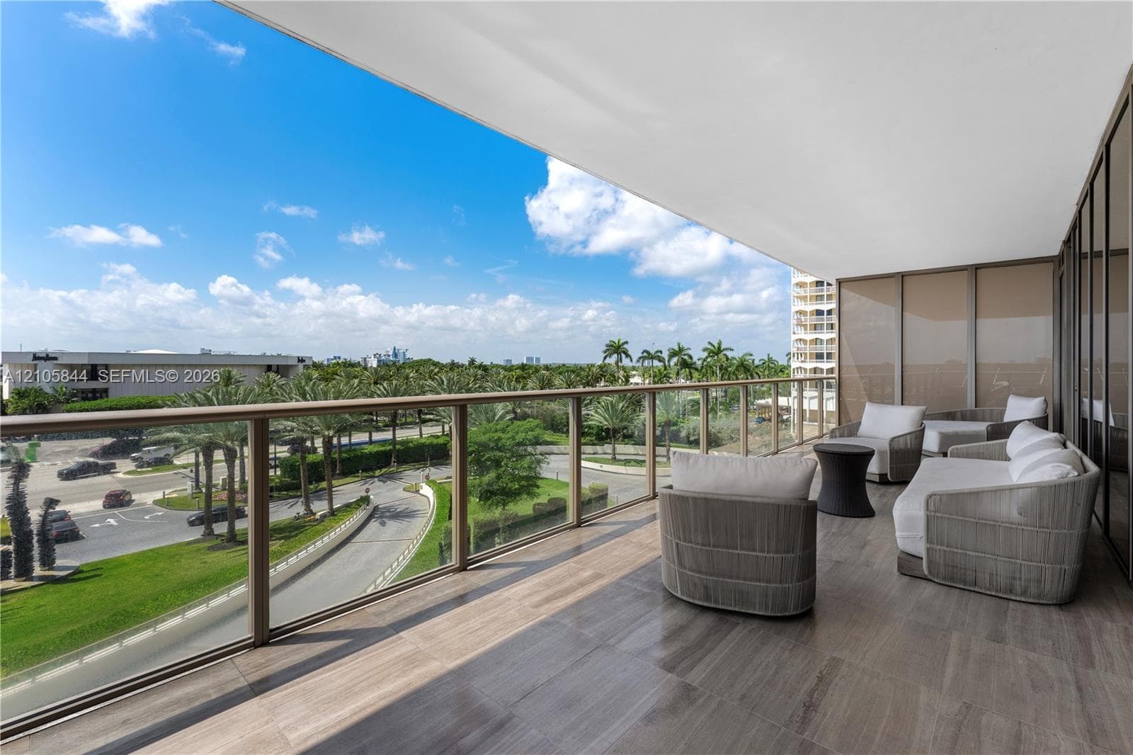 Expansive covered balcony featuring tile flooring and a metal-framed glass railing