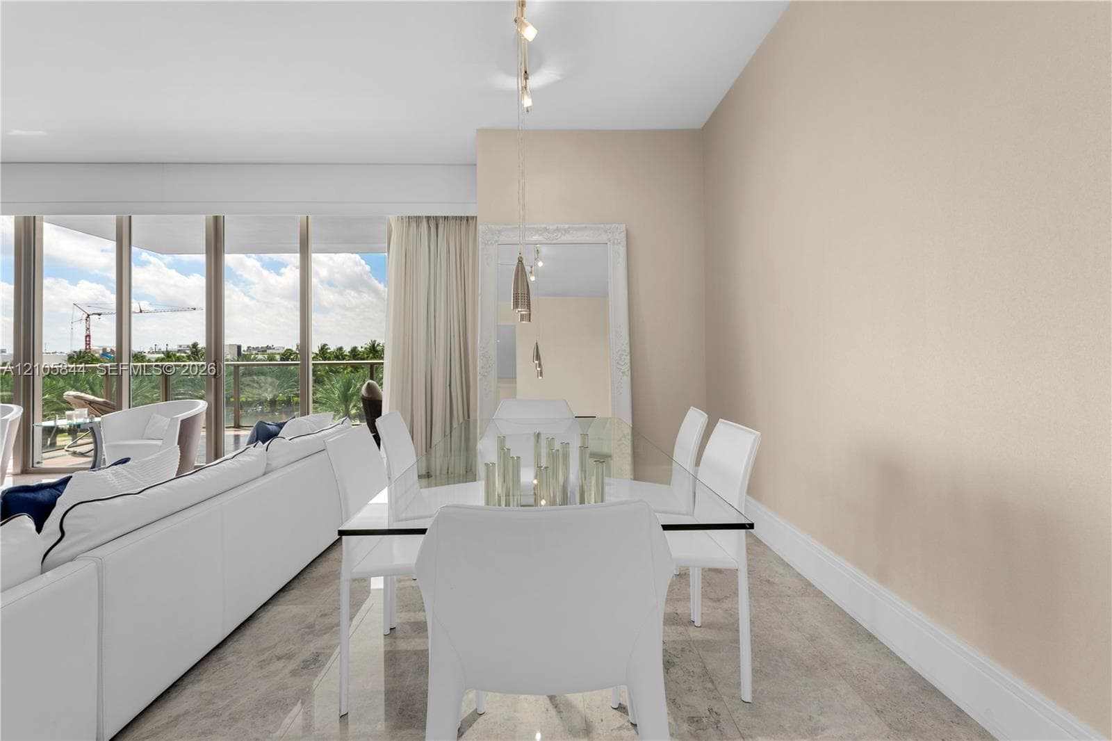 Open-concept space featuring floor-to-ceiling windows, natural stone flooring, and suspended pendant lighting
