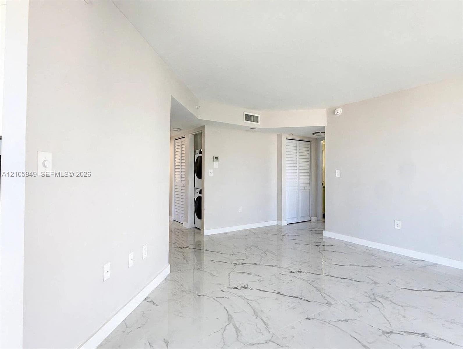Storage closet featuring white louvered double doors and interior white wire shelving