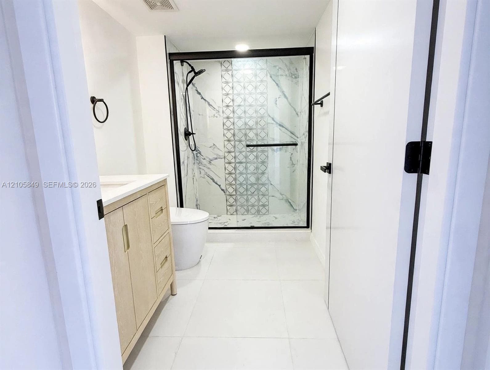 Large-format polished tile flooring, floor-to-ceiling sliding glass doors, and a private balcony with metal railing
