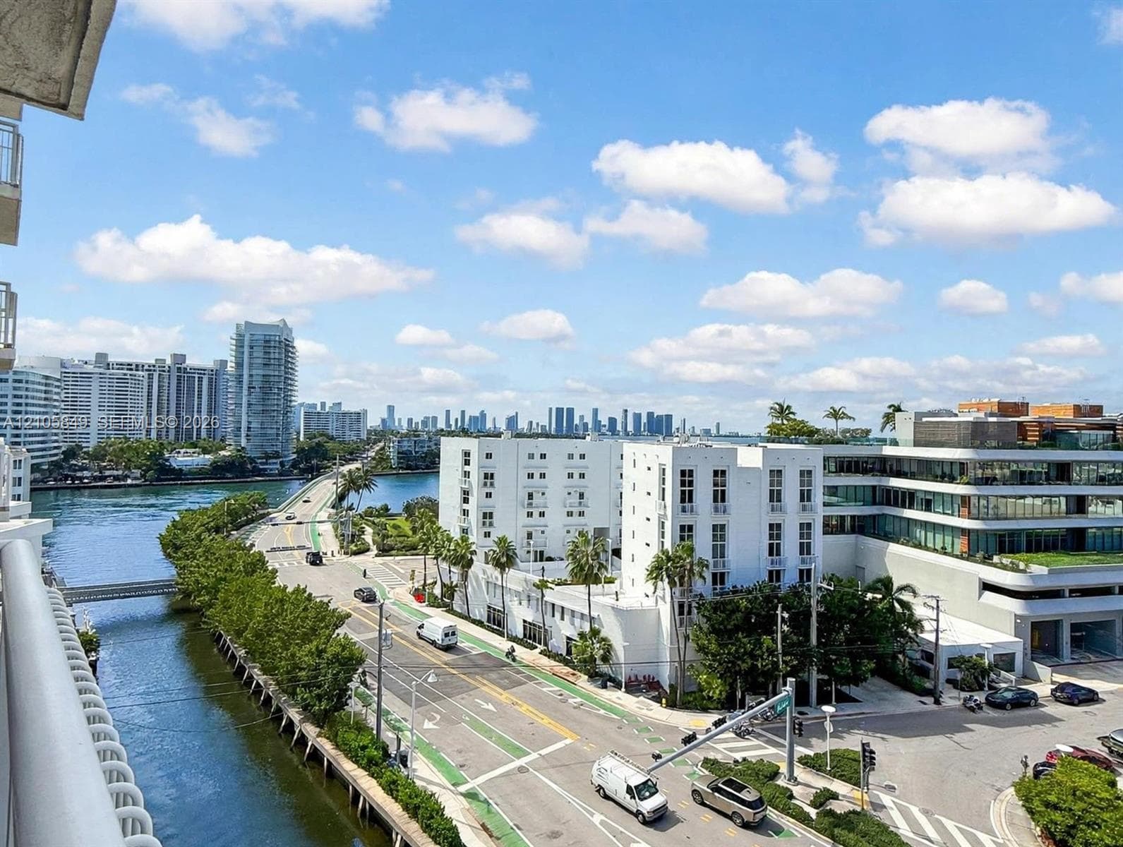 Aerial perspective featuring a multi-story white stucco exterior with recessed balconies and a skyline backdrop