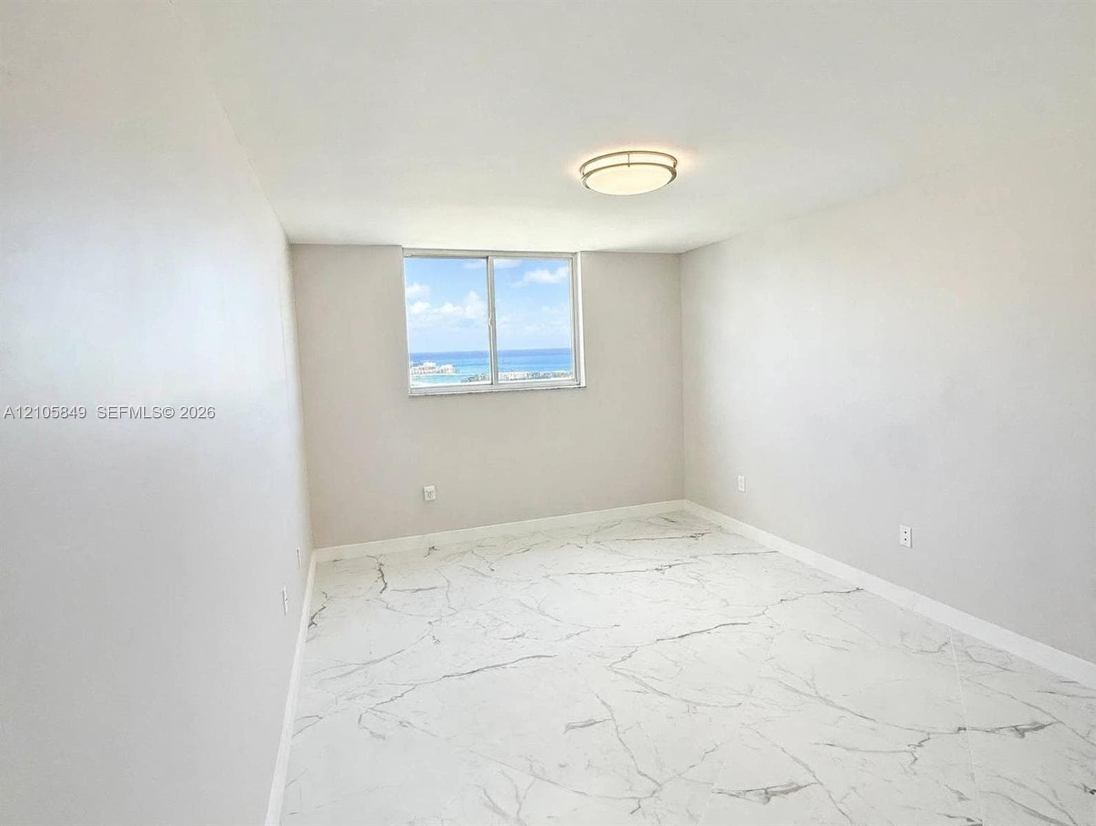 Neutral interior featuring stone-finish tile flooring, a sliding window, and a flush-mount ceiling fixture