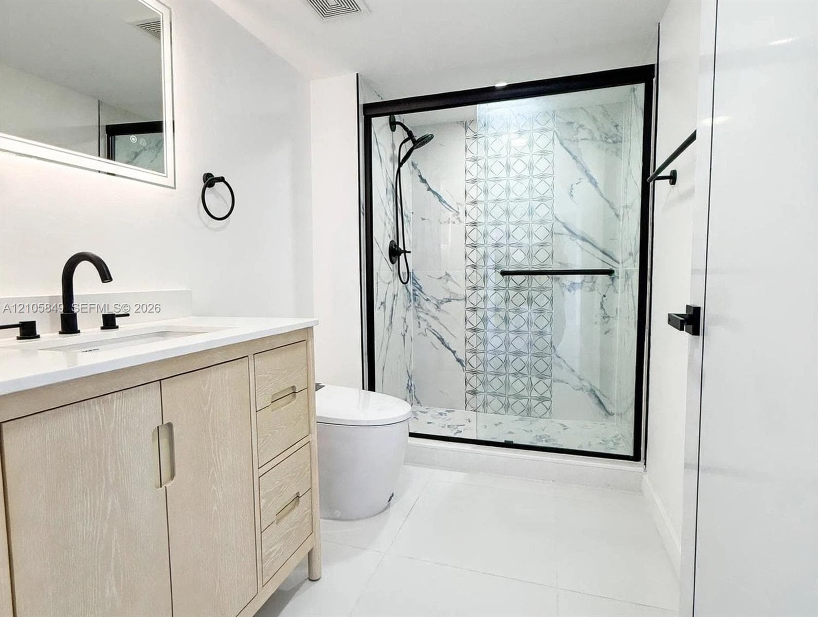 Light wood-finish vanity with a white countertop, rectangular undermount sink, matte black faucet, and an integrated backlit mirror