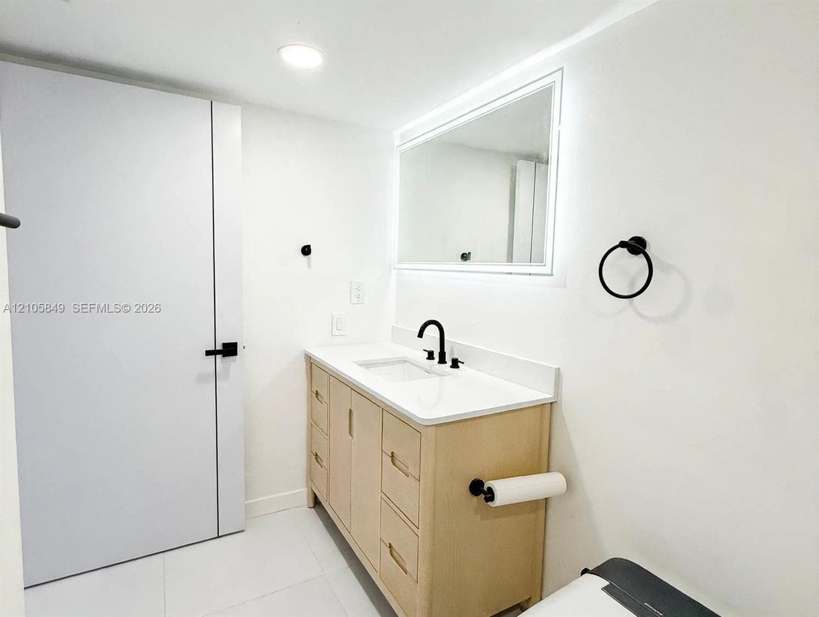 Neutral interior space featuring stone-finish flooring with veining, a flush-mount ceiling light fixture, and a window with an ocean horizon backdrop