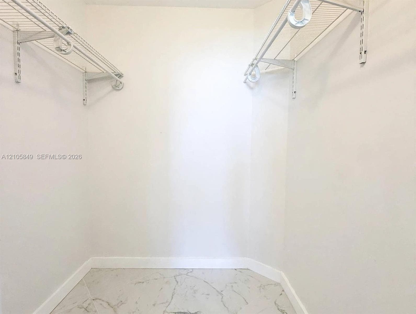 Bathtub with floor-to-ceiling marbled wall tile and decorative geometric tile inlay, complemented by matte black fixtures including a wall-mounted towel bar and circular ring