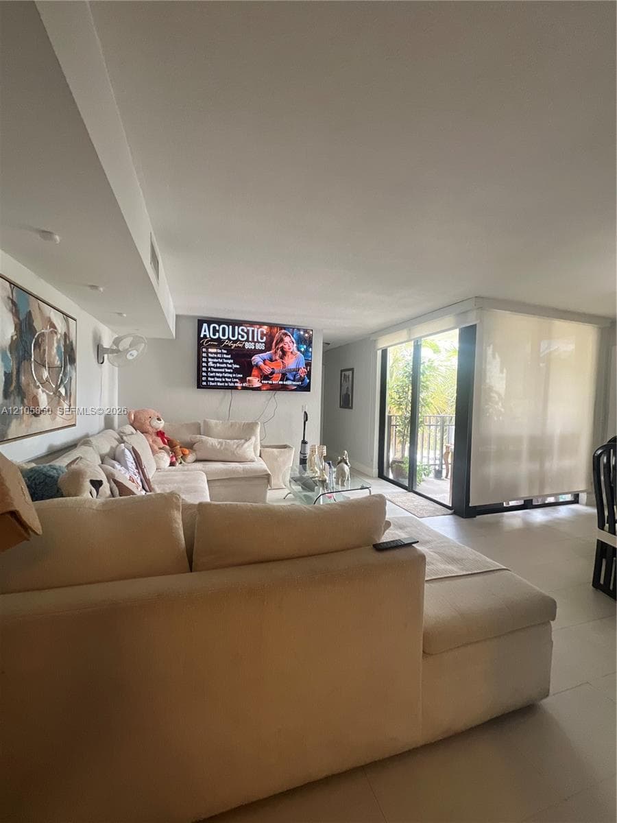 Living area featuring tile flooring, recessed lighting, and floor-to-ceiling sliding glass doors opening to a balcony