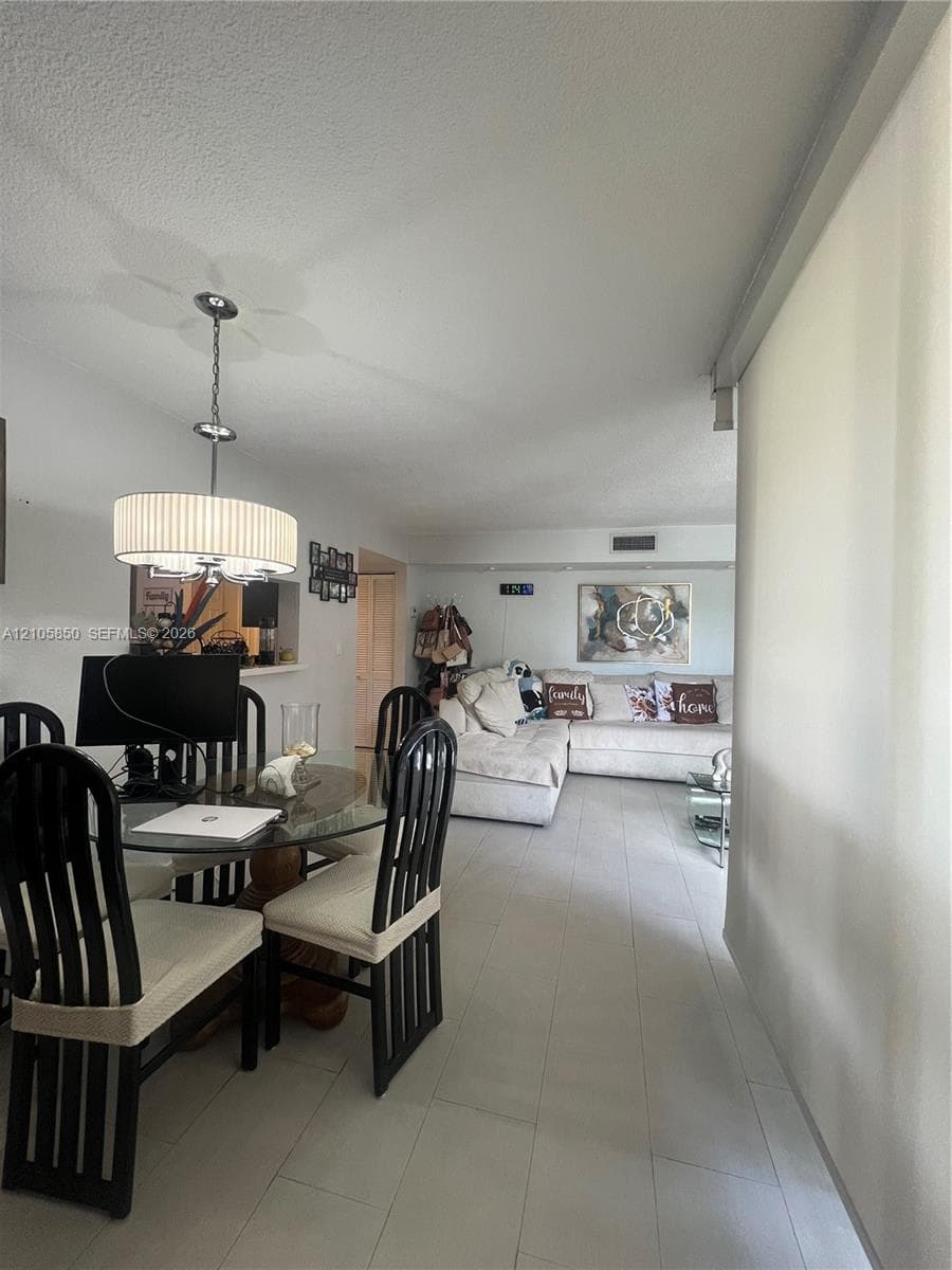 Neutral-toned ceramic tile flooring, drum-style pendant lighting with a metallic finish, and a pass-through opening