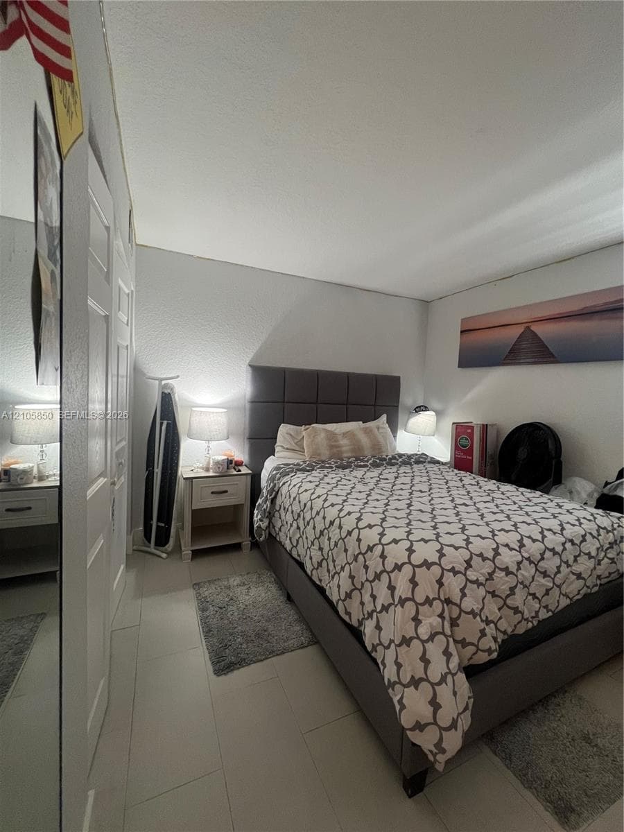 Neutral-toned room featuring large-format tile flooring and double-door closet storage