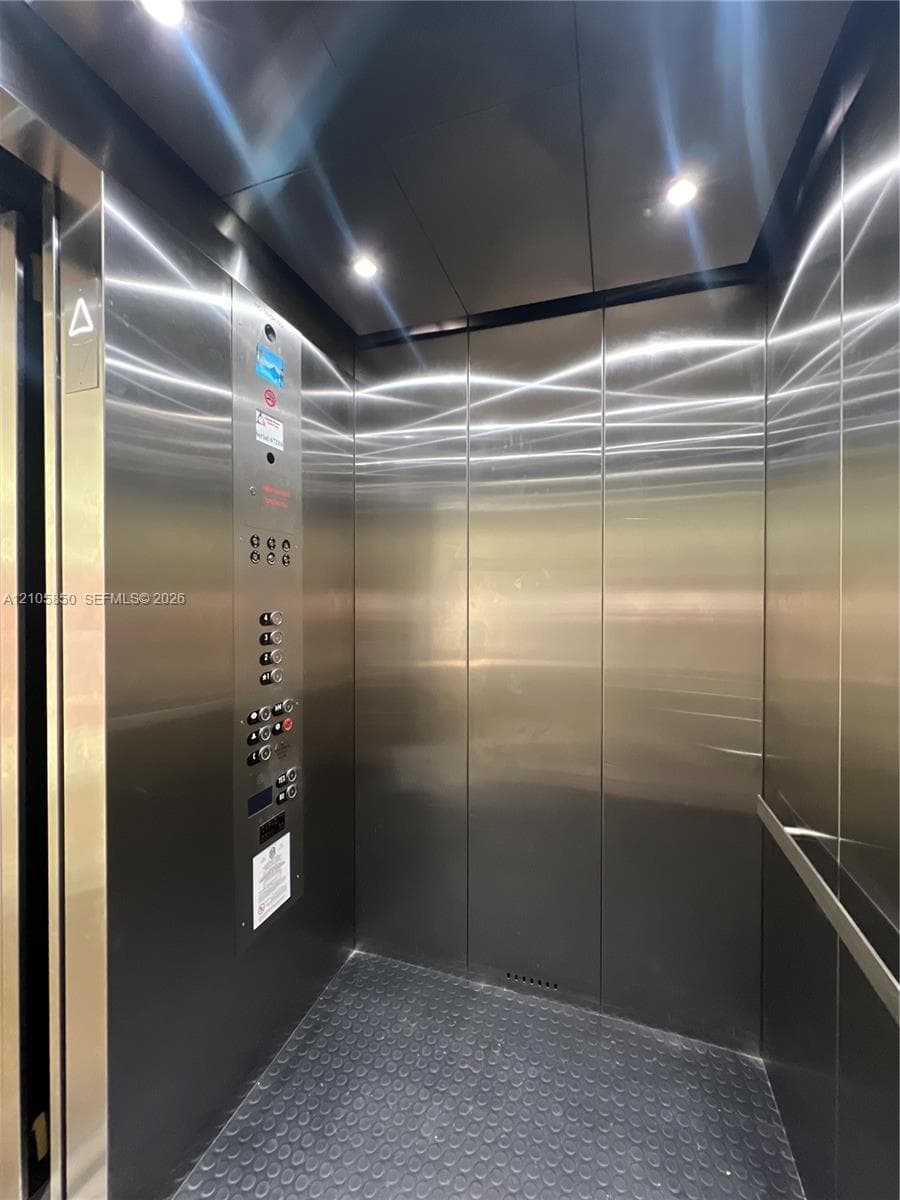 Elevator interior featuring brushed stainless steel paneling, recessed ceiling lighting, a textured rubberized floor, and an integrated control panel