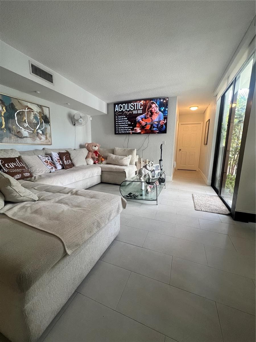 Living area featuring large-format neutral floor tile, sliding glass doors, and a recessed ceiling lighting fixture