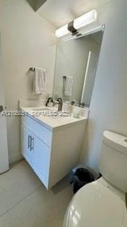 White vanity cabinet with a stone countertop, integrated sink, polished metal hardware, and full-length vanity mirror with overhead light fixture