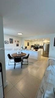 Kitchen featuring white cabinetry, stainless steel appliances, a stone countertop, and a breakfast bar, complemented by large-format tile flooring