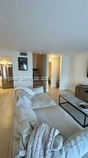 Interior featuring neutral tile flooring, stainless steel kitchen appliance, and carpeted stairs