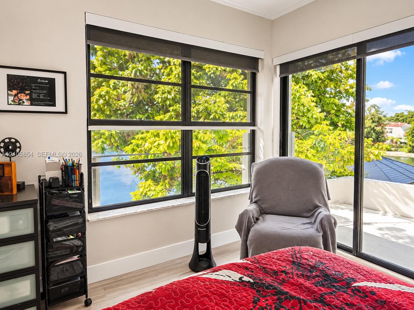 Spacious master bedroom featuring breathtaking lake views through an expansive window and sliding glass door, filling the room with natural light and creating a serene retreat.