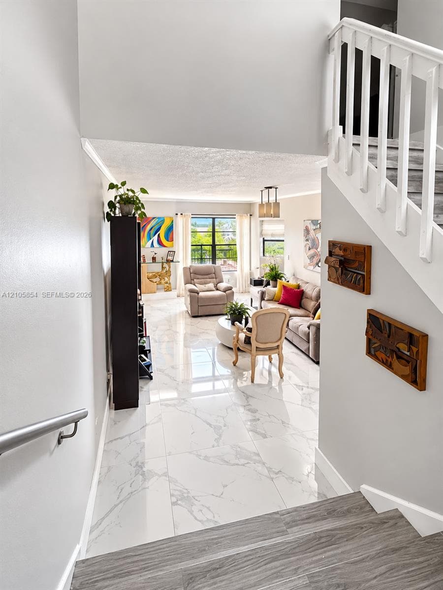 Large-format tile flooring with polished finish, staircase with wood-finish treads and white balusters, metal handrail. Beautiful lake views welcome you the moment you enter the home.