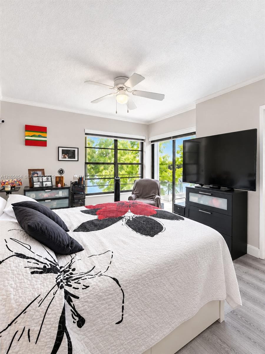 Spacious master bedroom featuring breathtaking lake views through an expansive window and sliding glass door, filling the room with natural light and creating a serene retreat.