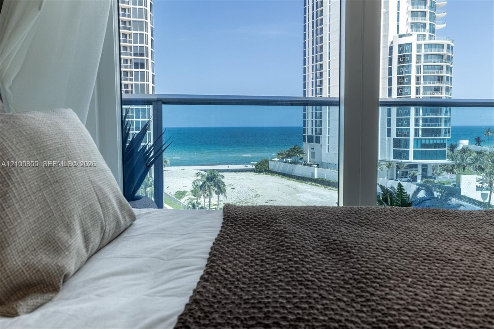 Floor-to-ceiling windows with a glass-paneled balcony overlooking the ocean and coastline