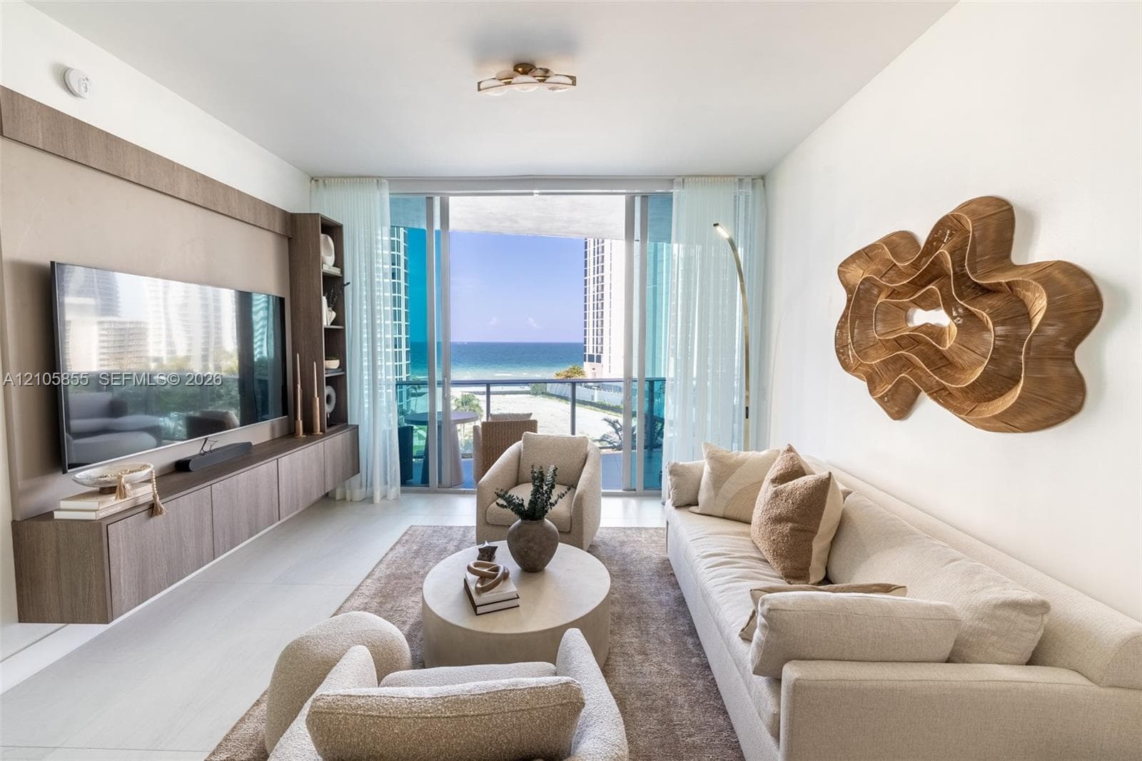 Living area featuring large-format light-toned flooring, floor-to-ceiling glass sliding doors, and custom built-in cabinetry with integrated shelving
