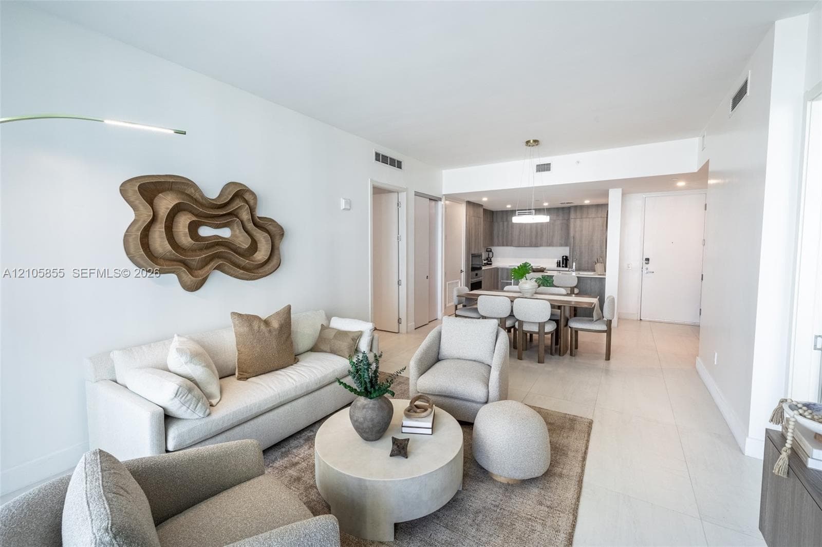 Open-concept floor plan featuring large-format tile flooring, recessed lighting, and kitchen cabinetry with a wood-grain finish