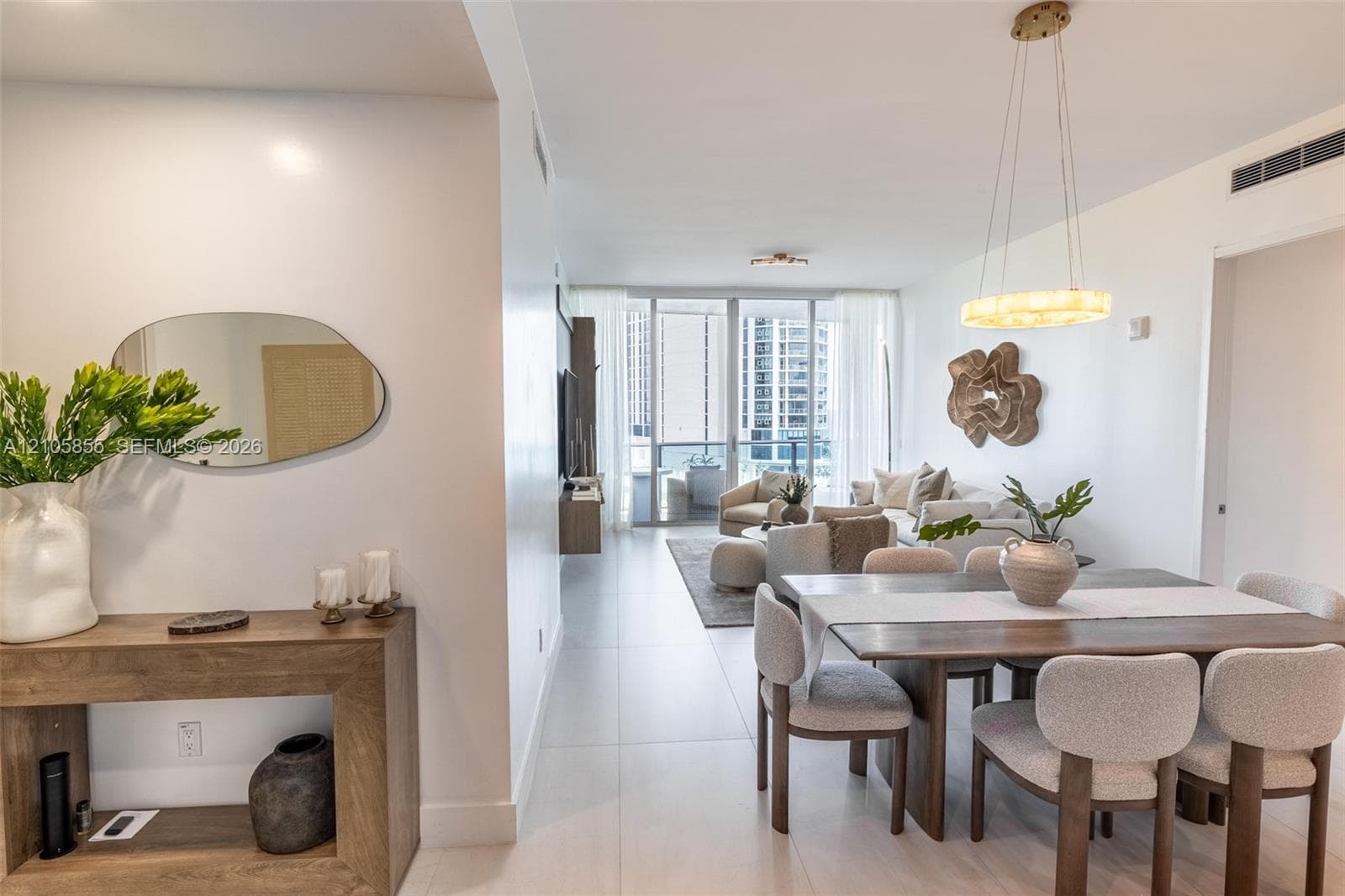 Large-format tile flooring, circular pendant lighting, and floor-to-ceiling glass doors opening to a balcony