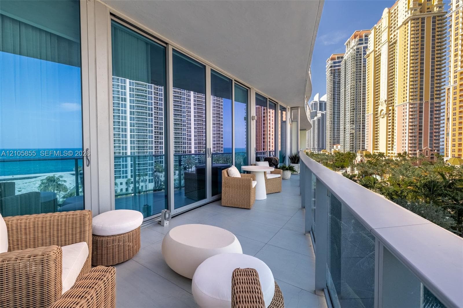 Expansive curved balcony featuring large-format tile flooring, a glass-panel railing, and floor-to-ceiling sliding glass doors