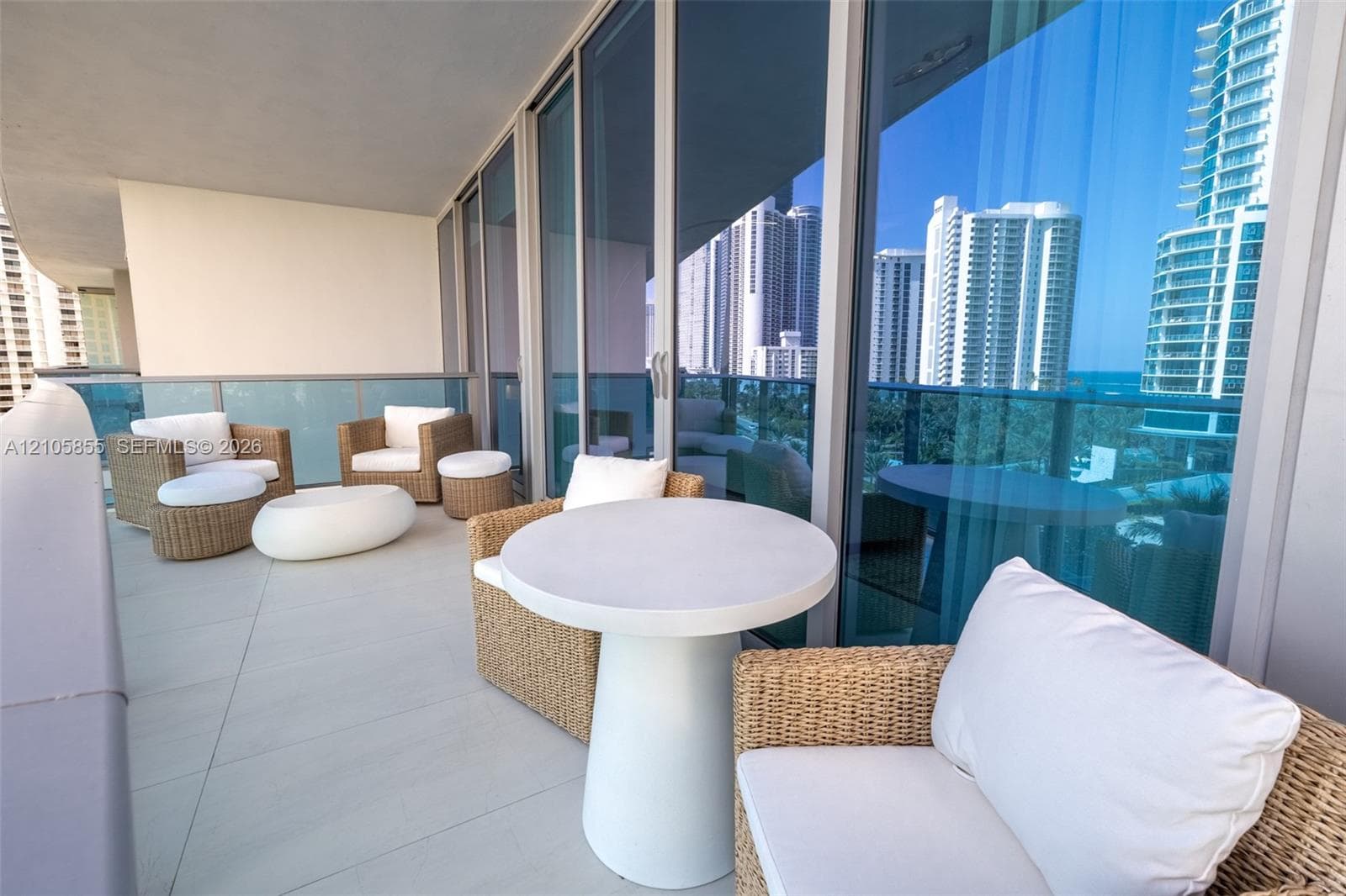 Covered balcony featuring oversized tile flooring, full-height glass sliding doors, and glass-paneled railings