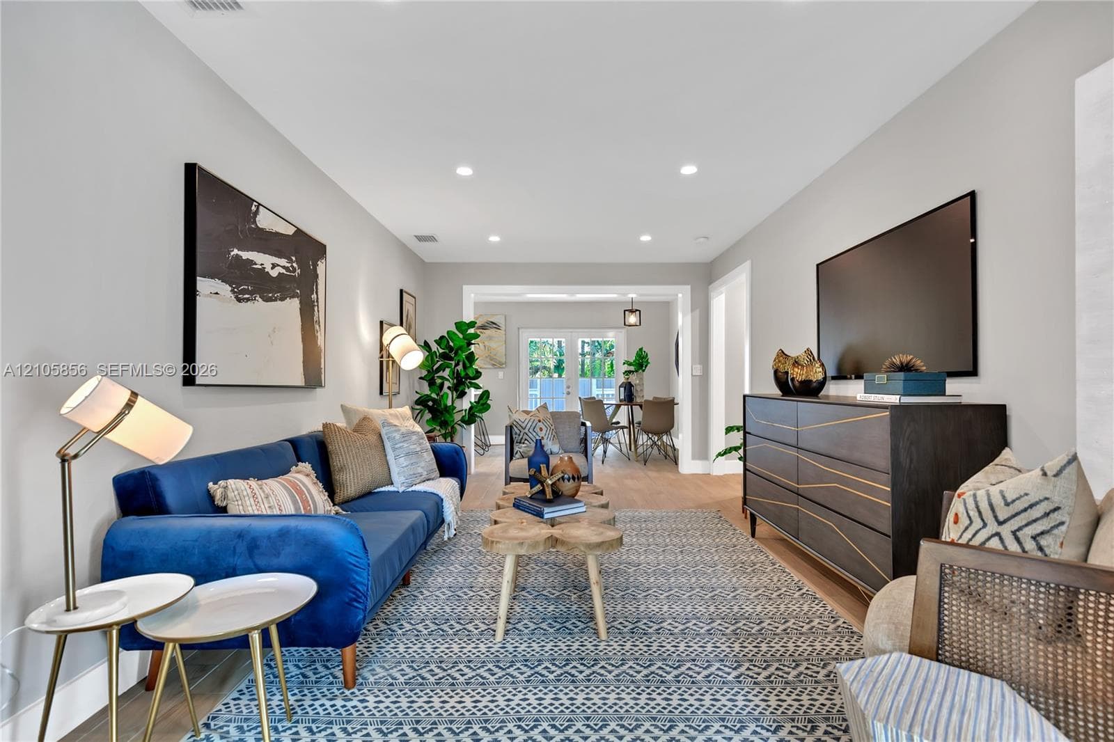 Open-concept interior featuring wood-finish flooring, recessed lighting, and white glass-paneled double doors leading to the exterior
