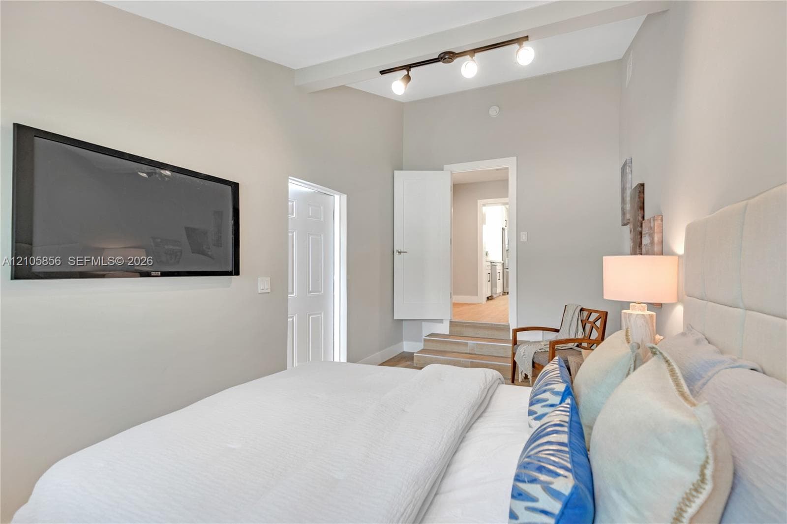 High-ceiling bedroom featuring track lighting, solid-core doors, and stepped flooring