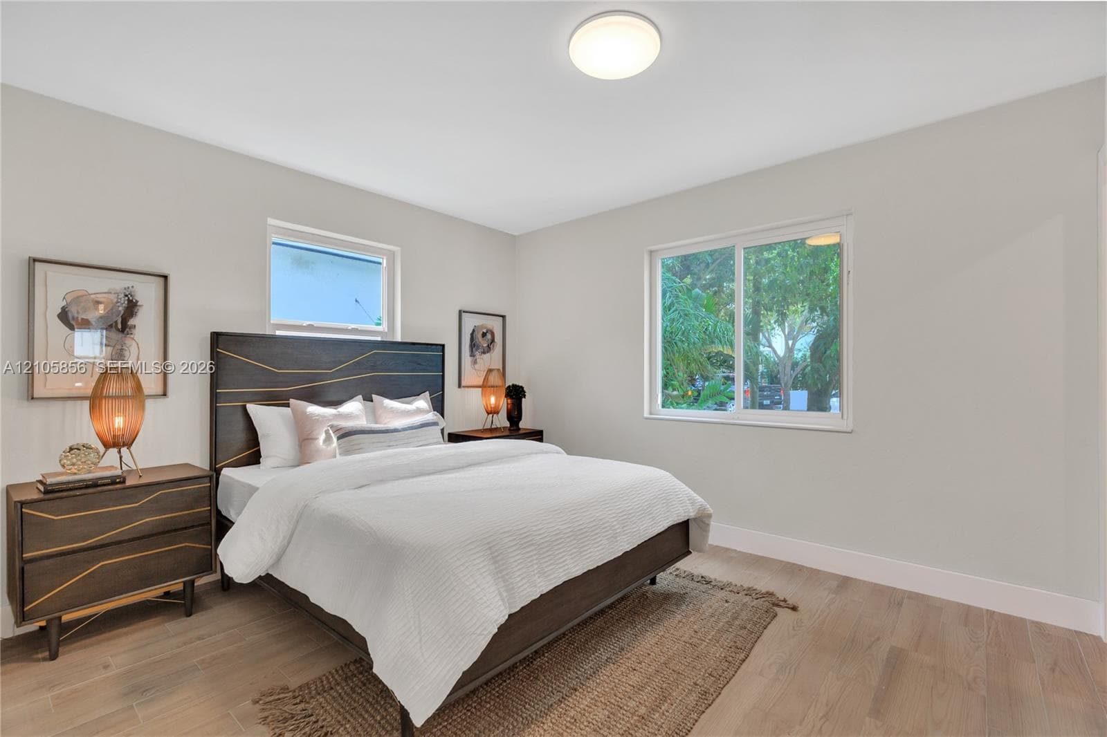 Neutral-toned walls, wood-finish flooring, dual windows, and a flush-mount overhead light fixture