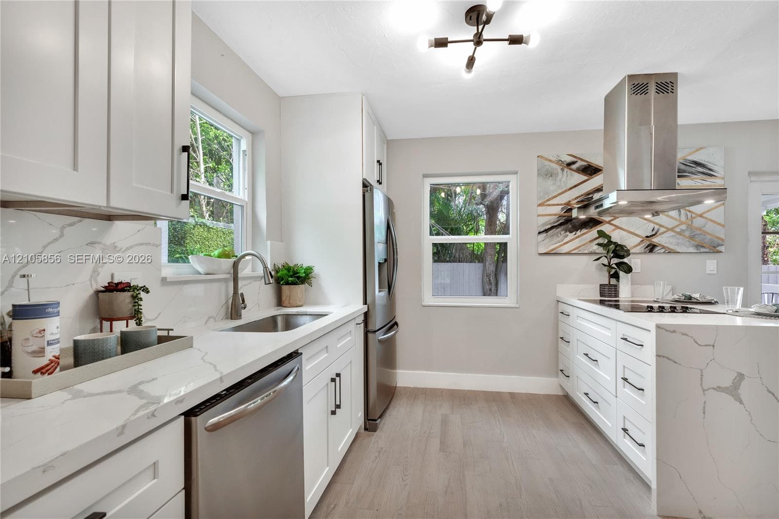Kitchen featuring white cabinetry with matte black hardware, stone-finish countertops, stainless steel appliances, a stainless steel range hood, and wood-finish flooring