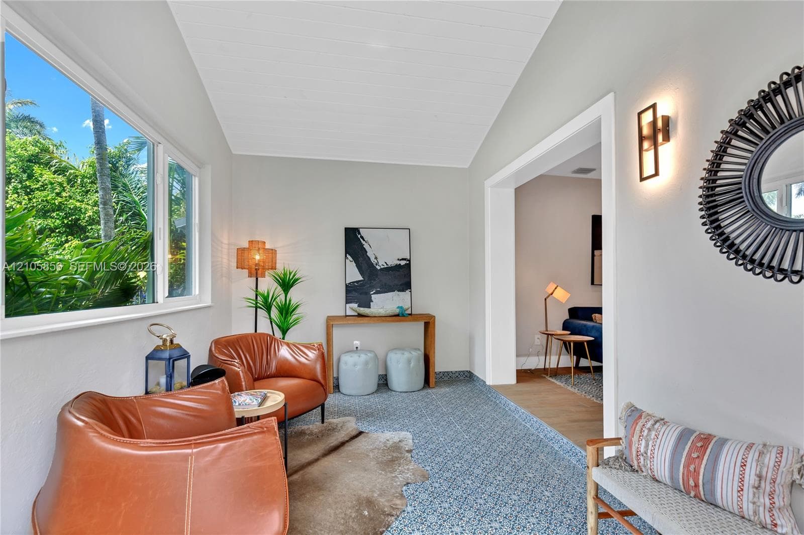 Vaulted ceiling with shiplap detail, large-format picture window, and wall-mounted sconce lighting