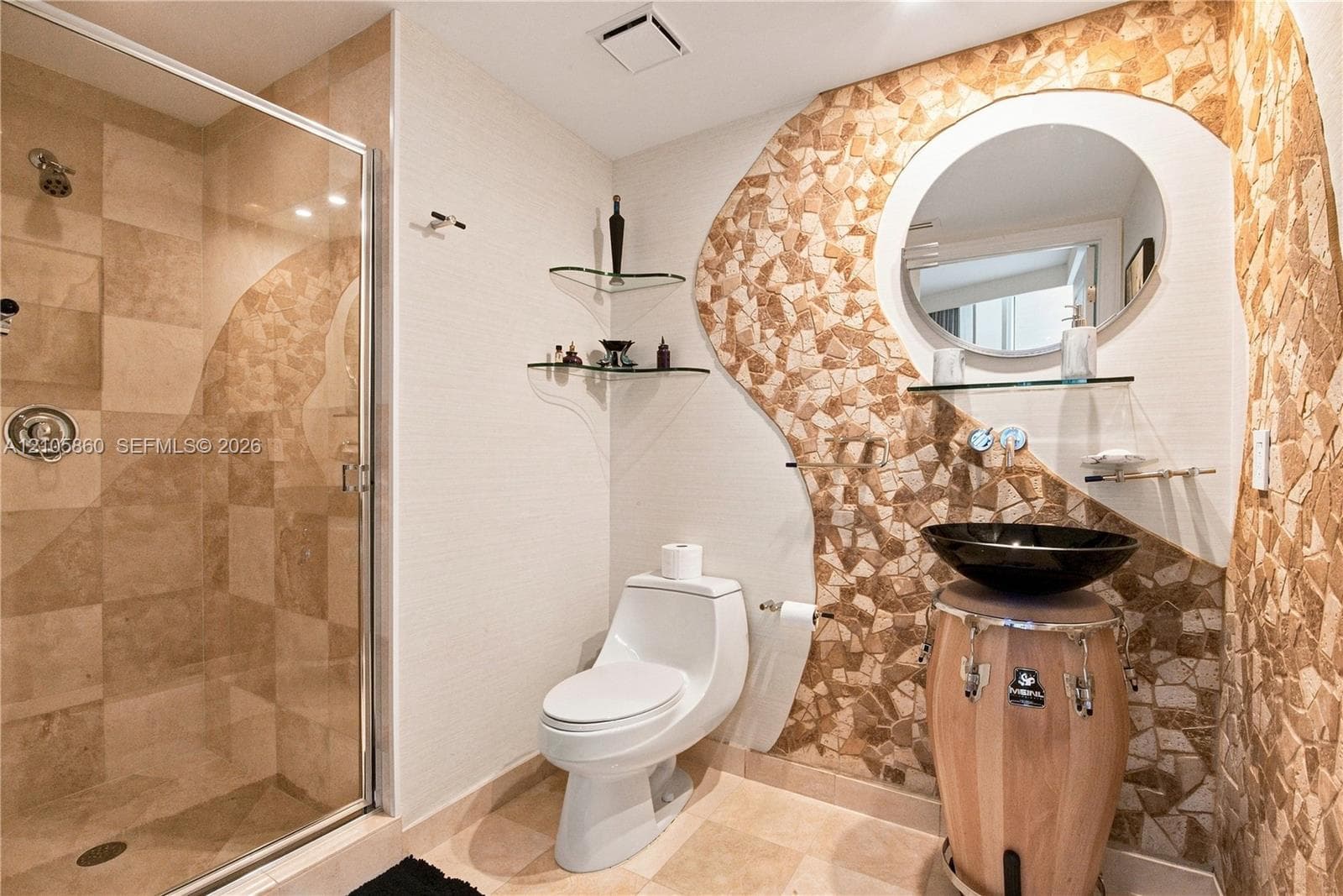 Bathroom featuring a glass-enclosed shower with tiled surround, stone mosaic wall accents, oval wall-mounted mirror, and glass corner shelving