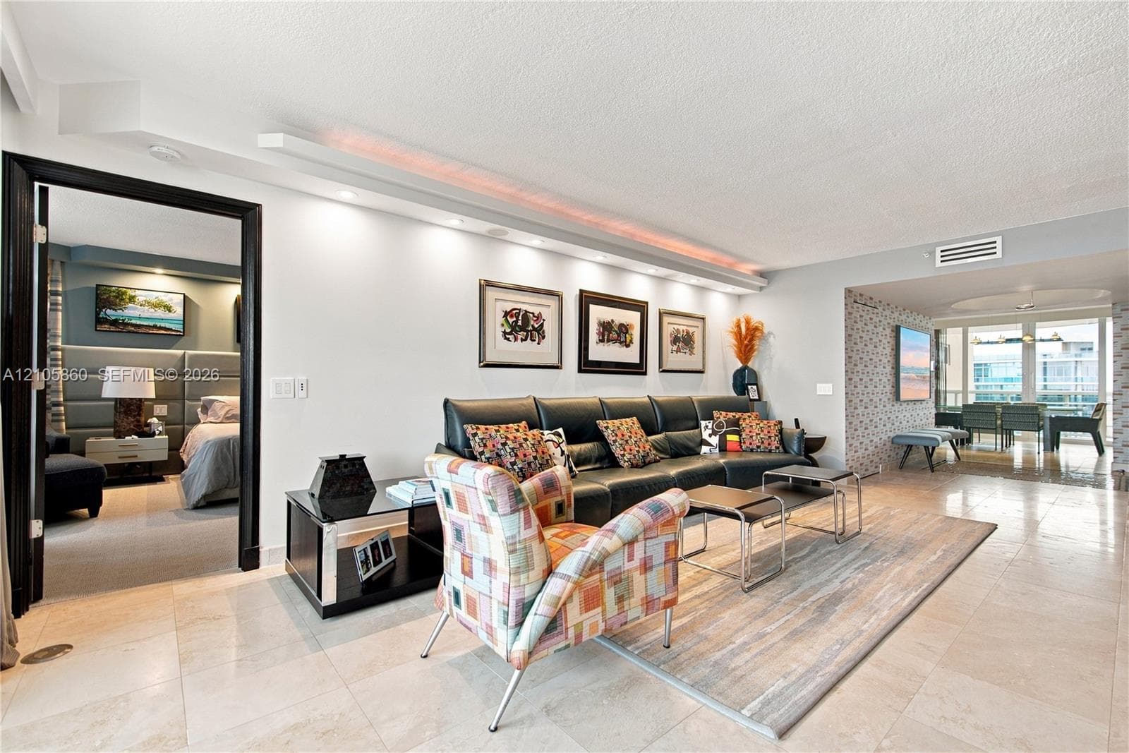 Open-concept living area featuring stone tile flooring, built-in cove lighting, and a distinct entryway with high-contrast black trim